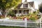 cozy house with warm and welcoming exterior, including a white picket fence and blooming flowers