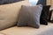 Cozy interior details. Decorative pillows in neutral colors, plaid on beige textile sofa. Home comfort concept, textiles,