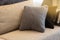 Cozy interior details. Decorative pillows in neutral colors, plaid on beige textile sofa, warm highlight. Home comfort concept,