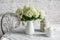 Cozy kitchen in scandinavian style. Bouquet of hydrangeas, teapot, metal jar on the table in a bright room. Cozy home concept