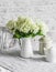 Cozy kitchen in scandinavian style. Bouquet of hydrangeas  teapot  metal jar on the table in a bright room. Cozy home concept