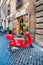 Cozy narrow ancient medieval Old Town paving stone street with coffee bars, small businesses, parked red vintage mopeds in Rome,