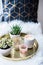 Cozy real home decoration, burning candles on golden tray with pillow on white faux fur on windowsill