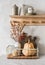 Cozy scandinavian style kitchen. Metal box on the table with cutting boards, pumpkin, dried flowers and a wooden shelf with dishes