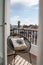 Cozy shot of outdoor balcony with chair and pillow in background of buildings