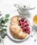 Cozy snack - croissant, fresh raspberries and green tea on a white background, top view