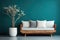 Cozy sofa with white cushions and tree in big wooden pot against teal wall with frame