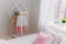 Cozy spacious light room with fashionable clothes on hangers, comfortable bed with white bedroom, white walls. Domestic atmosphere