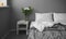 Cozy summer corner of the lounge, background or mood screen. white nightstand with a vase of flowers and books. bed by