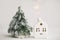 Cozy winter home, christmas scene, miniature house with lights and snowy tree. Merry Christmas