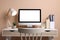 Cozy workspace with computer, lamp, houseplant and stationery on wooden desk