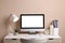 Cozy workspace with computer, lamp, houseplant and stationery on wooden desk