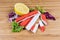 Crab sticks, lemon and variegated lettuce leaves on cutting board