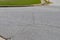 Cracked asphalt intersection with formed curbs and green grass border, aged and weathered street surface