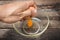 Cracked chicken egg with yolk and egg shell on dish, wooden background