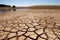 Cracked earth with dried up lake in background. Global warming and water scarcity concept