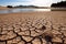 Cracked earth with dried up lake in background. Global warming and water scarcity concept