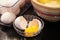 Cracked eggshell with double yolk egg next to vintage stoneware bowl