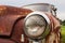 Cracked Headlight On Old Rusted Junkyard Car