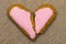 Cracked heart shaped cookie decorated with red icing as a concept of broken heart