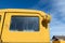 The cracked rear cab window of a rusty yellow antique truck