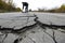 cracked road with person inspecting damage