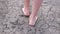 Cracked soil. Feet of a girl walking barefoot on the bottom of a dried lake or river.