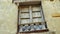 Cracked stone wall of an abandoned house with an old window with closed wooden shutters.