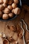 Cracked walnuts and kernels near the bowl with nuts and nutcracker on rustic wooden surface