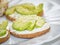 Crackers with avocado slices, cream cheese and sesame on the white dish. Healthy diet. Closeup