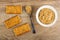 Crackers with sesame, flaxseed, spoon with peanut butter, bowl with peanut butter on table. Top view