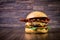 Craft beef burger with cheese, bacon, caramelized onion and rocket leafs on wood table and rustic background