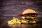 Craft beef burger with cheese, bacon, rocket leafs, caramelize onion and french fries on wood table and rustic background