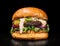 Craft burger is cooking on black background. Consist: sauce salsa, lettuce, red onion, pickle, cheese, chilli green