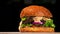 Craft burger is cooking on black background. Consist: sauce salsa, lettuce, red onion, pickle, cheese, chilli green