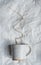 Craft ceramic mug with sand texture  with brown wire as coffee smoke on white crumpled paper, handmade craft pottery, background