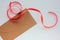 Craft envelop with heart and red ribbon on white background. Top view, copy space