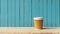 craft paper coffee cup on wooden table, blue wooden wall background