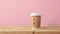 craft paper coffee cup on wooden table, pink wall background with copy space
