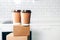Craft paper cups with coffee to go and food box, lunch on tabletop over white kitchen. Banner, copy space. Safe delivery, take