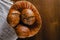 Craft three bread buns in a wicker basket, on a wooden cutting board. Simple breakfast on wooden background. copy space.