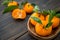 A craft wooden plate of fresh orange clementine tangerines with