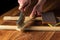 The craftsman cleans the wood plank with an abrasive tool. Builder hands close up. Renovation or construction idea