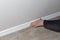 The craftsman installs a white plastic skirting board. Home and office renovation and improvement