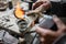 A craftsman jeweler is pouring some melted silver in a mold to make an unique piece