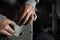 A craftsman jeweler is using a sandpaper to tile a metal cilinder for a bracelet