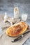 Craftsman sliced toast bread with butter on a wooden cutting board and milk. Simple breakfast on a gray concrete background. Close