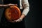 Craftsmanship hands have a typical Italian cheese. French tomme cheese in the hands of a cheesemaker on dark background. Different