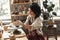 Craftsperson Concept. Young woman sitting at table making pottery indoors rolling clay making shape concentrated