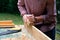 Craftswoman working with carpentry plane outdoors. Close-up view. Woodworking concept